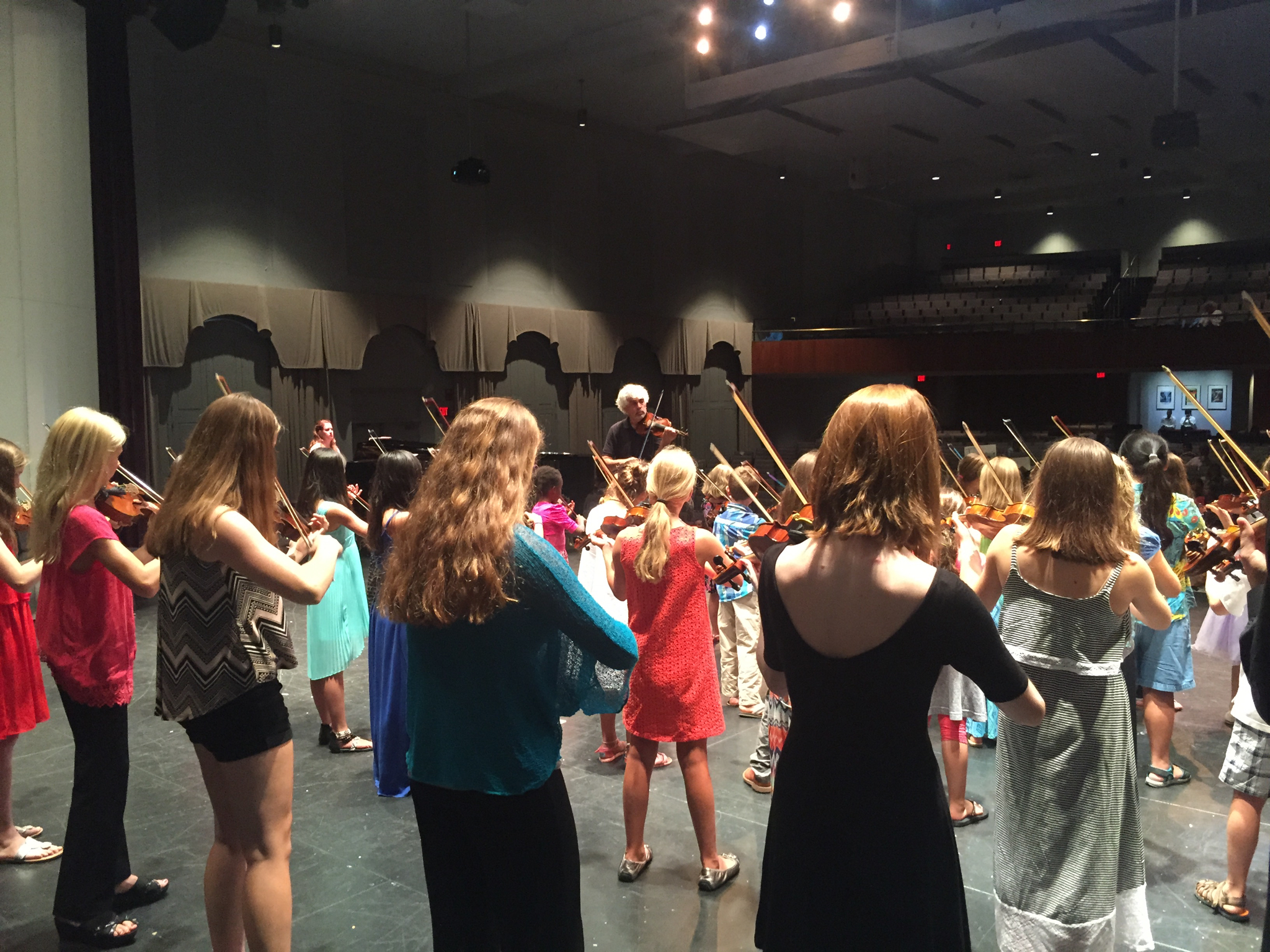 Students performing Suzuki Method with instructor on stage